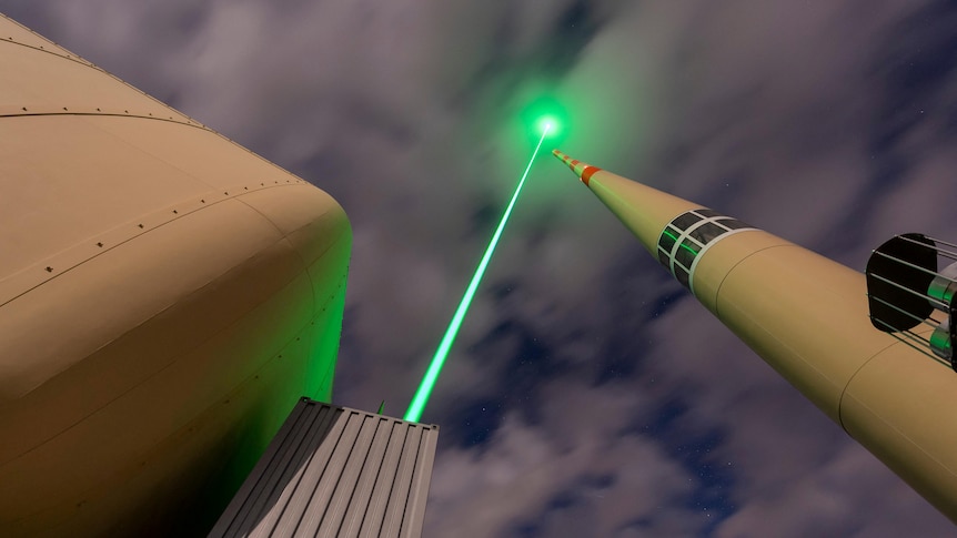 A large tower-like structure is pictured with a green laser coming out of it. 