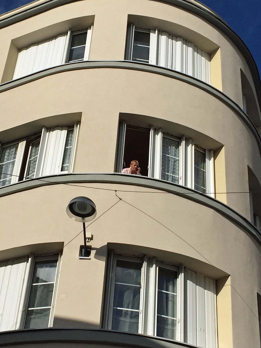 A Saint-Denis resident watches the media crush below.