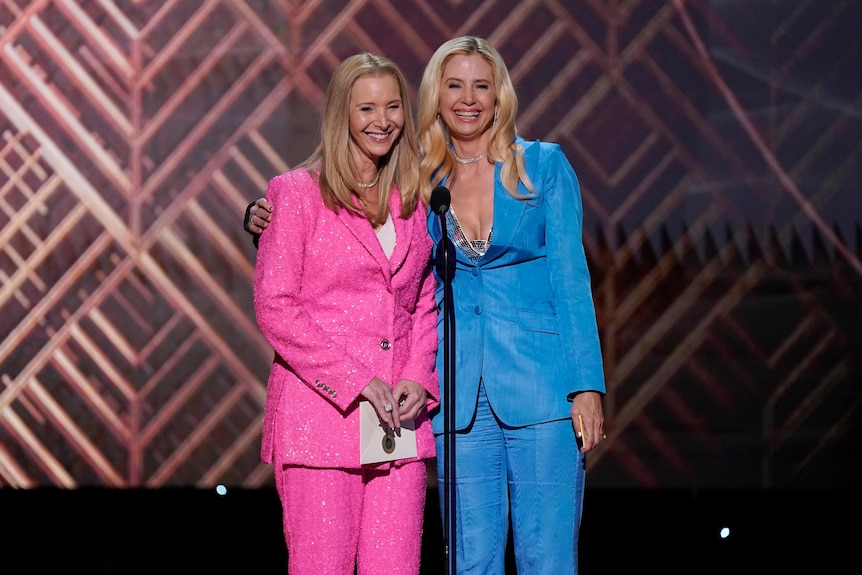 Lisa Kudrow wears a pink suit with Mira Sorvino wearing a light blue suit. 