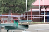 Police tape cordons off a basketball court in a school.