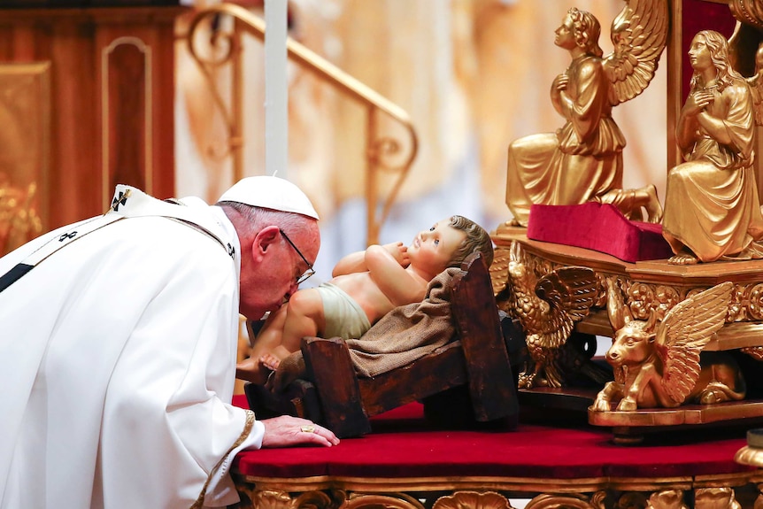 Pope Francis kisses a statue of baby Jesus.