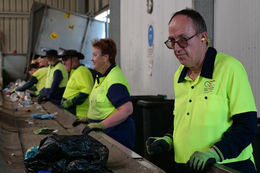 Conveyor belt with recycling, workers on right hand side. 