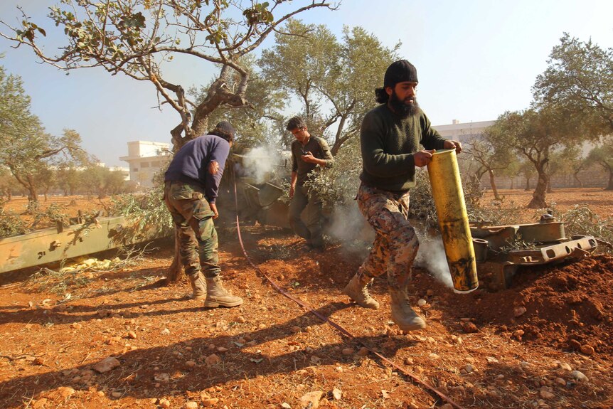 A rebel fighter carries an empty smoking shell in Dahiyet al-Assad.