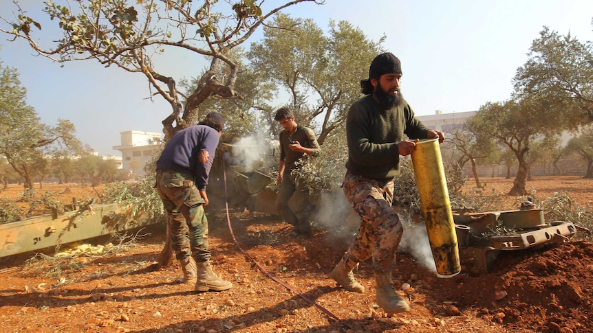 A rebel fighter carries an empty smoking shell in Dahiyet al-Assad.