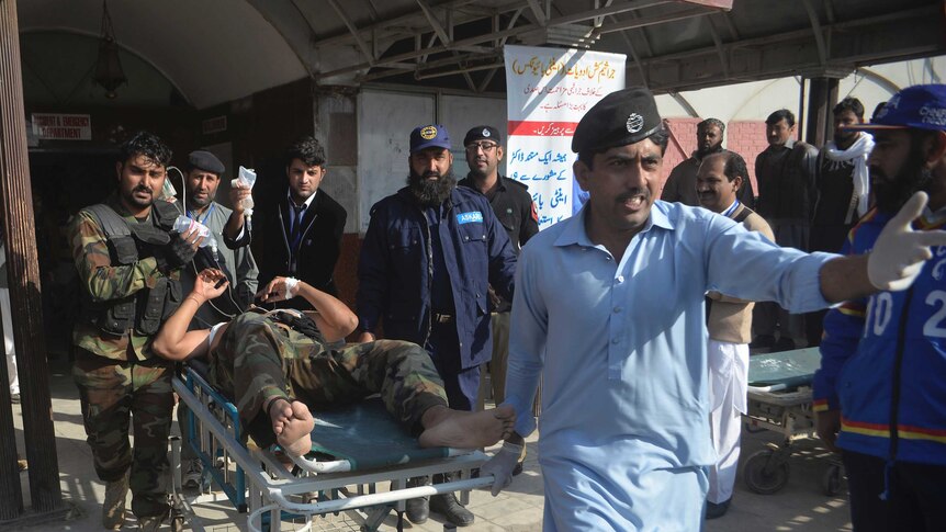 Hospital staff and soldiers wheel out a victim on a stretcher.