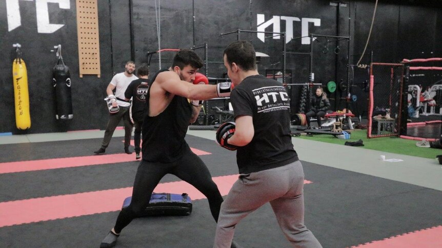 Two mixed martial arts fighters train in a gymnasium