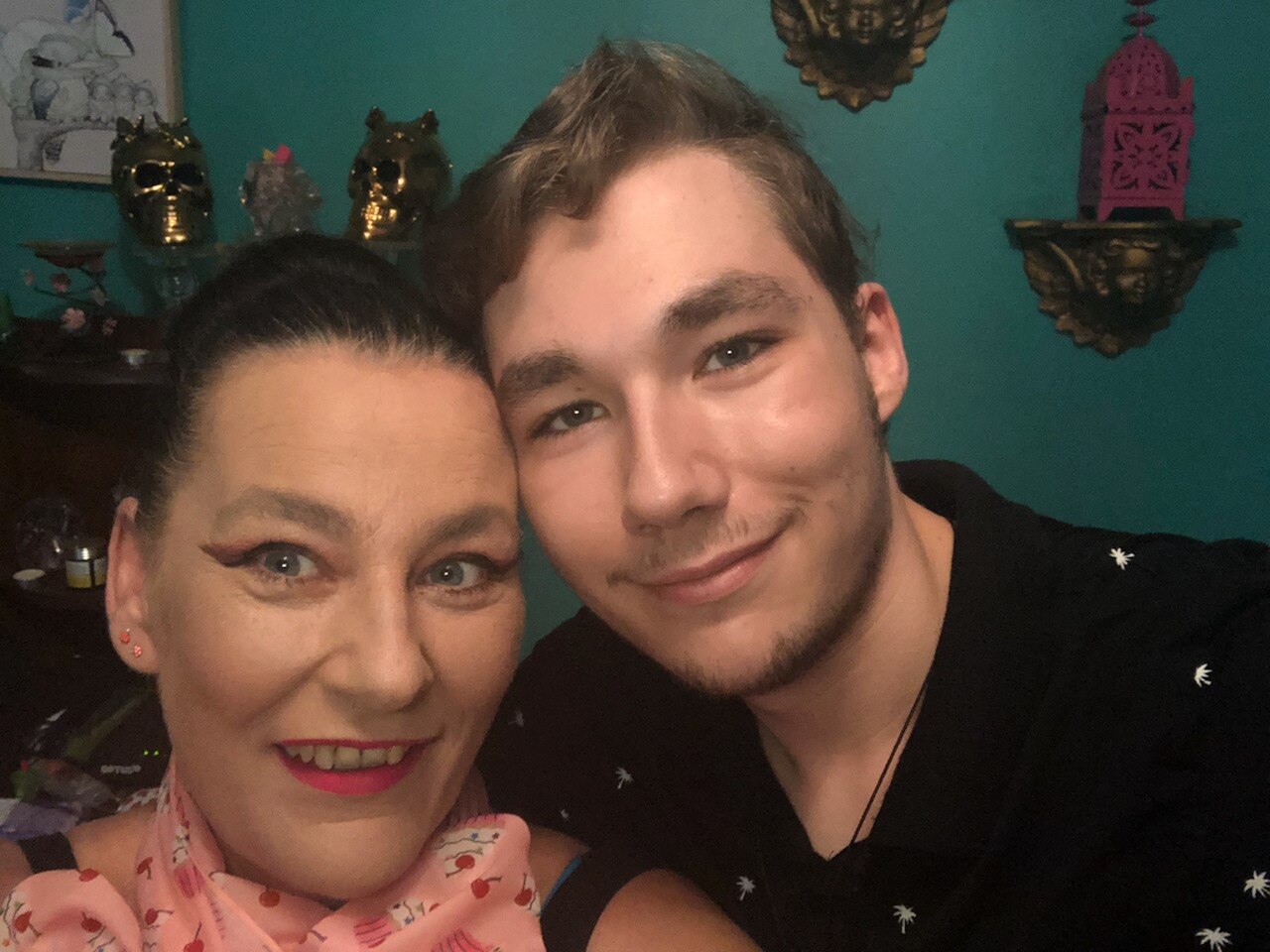 An image of a young man pressing his cheek to his mother's temple, with both smiling