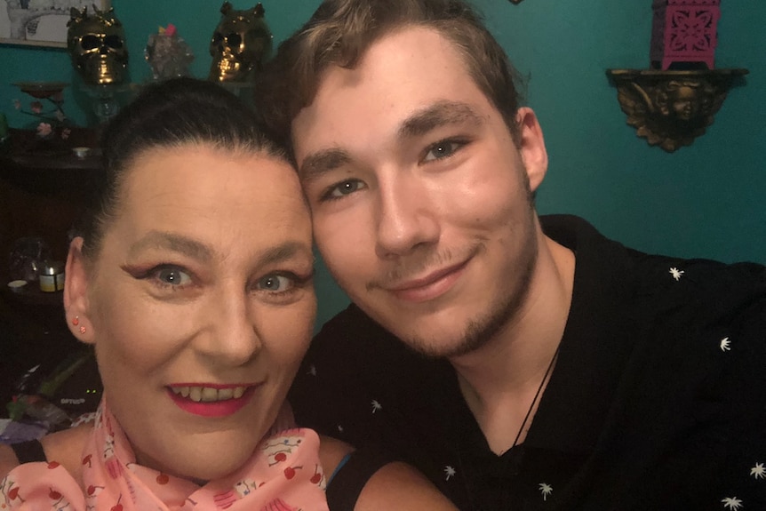 An image of a young man pressing his cheek to his mother's temple, with both smiling