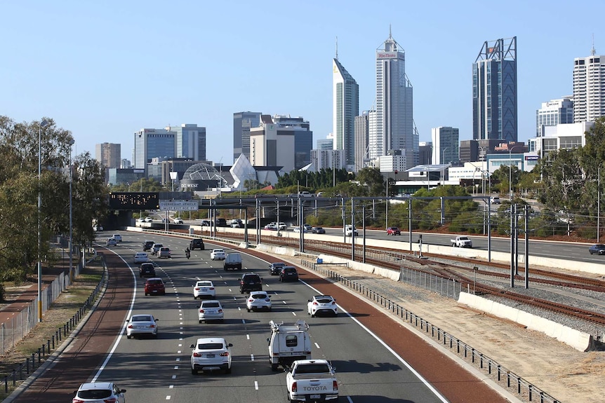A wide shot of south-bound traffic on the Mitchell Freeway heading into the Perth CBD with city buildings in the background.
