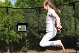Girl jumping on Smart Trampoline while looking at a tablet.