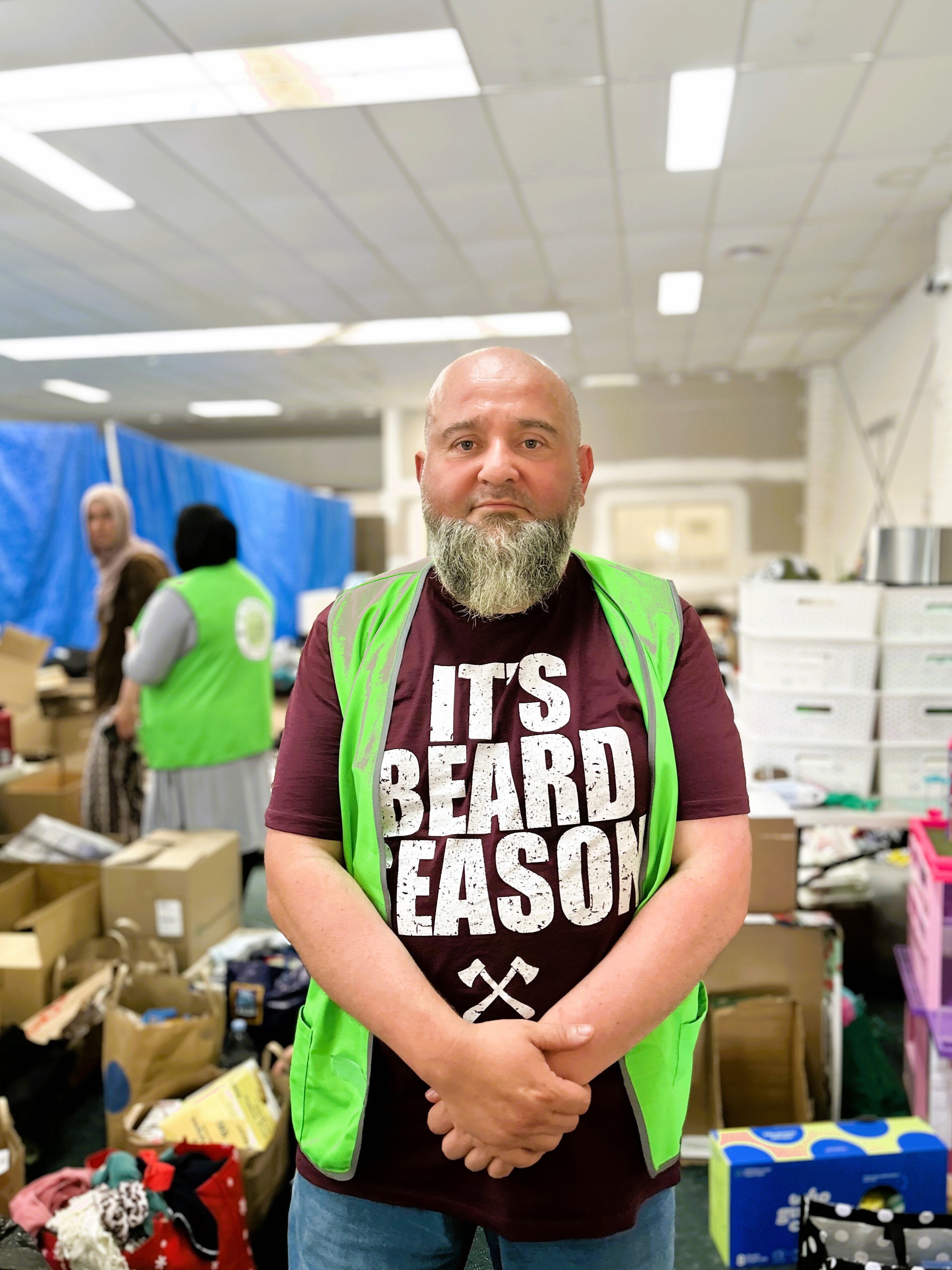 A photo of a man wearing a green hi-vis and a shirt that says 'ti's beard season'.