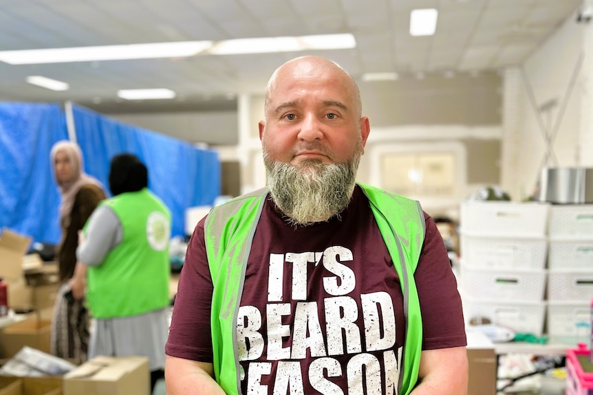 A photo of a man wearing a green hi-vis and a shirt that says 'ti's beard season'.