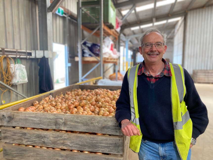 A man standing next to a box of onions