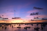 Boats drift in a small port at sunset in Bali.