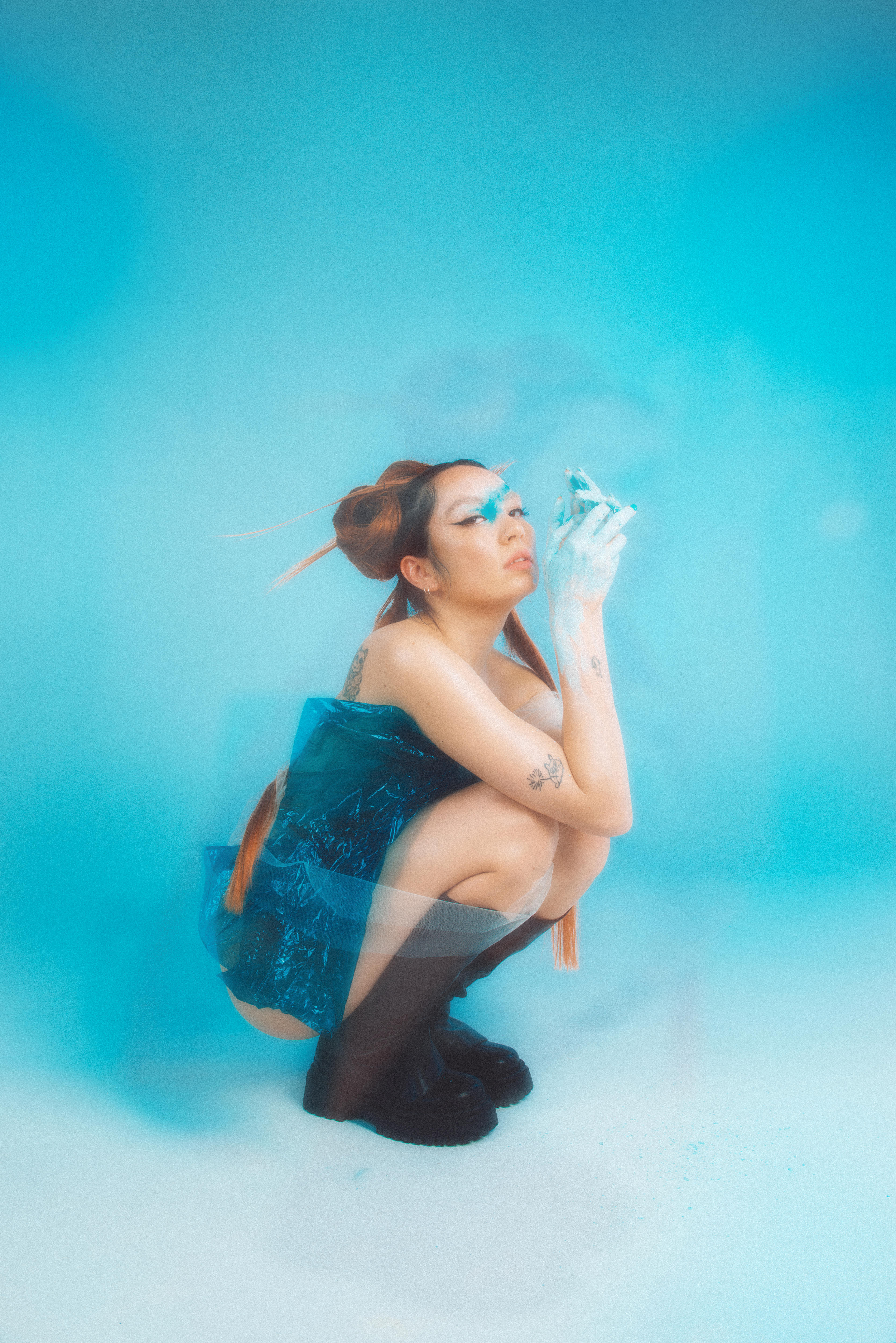 Jaguar Jonze, a Taiwanese Australian woman with brown and copper hair in a traditional Japanese style crouches in blue dress.