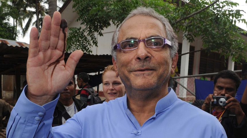 Jose Ramos-Horta waves with his inked finger after voting at a polling centre