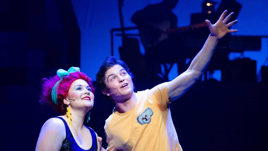 A man and woman in 80s clothing on stage in the musical Starstruck