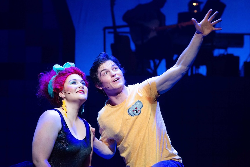 A man and woman in 80s clothing on stage in the musical Starstruck