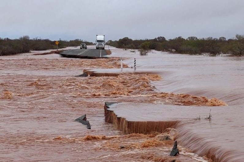 Raging floodwaters with trapped vehicles on an island.