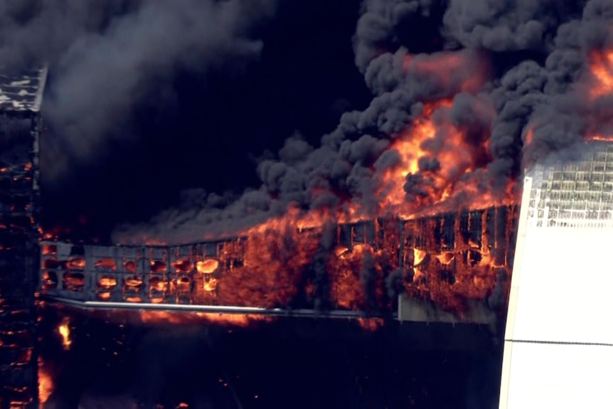 Flames lick out of a large industrial structure