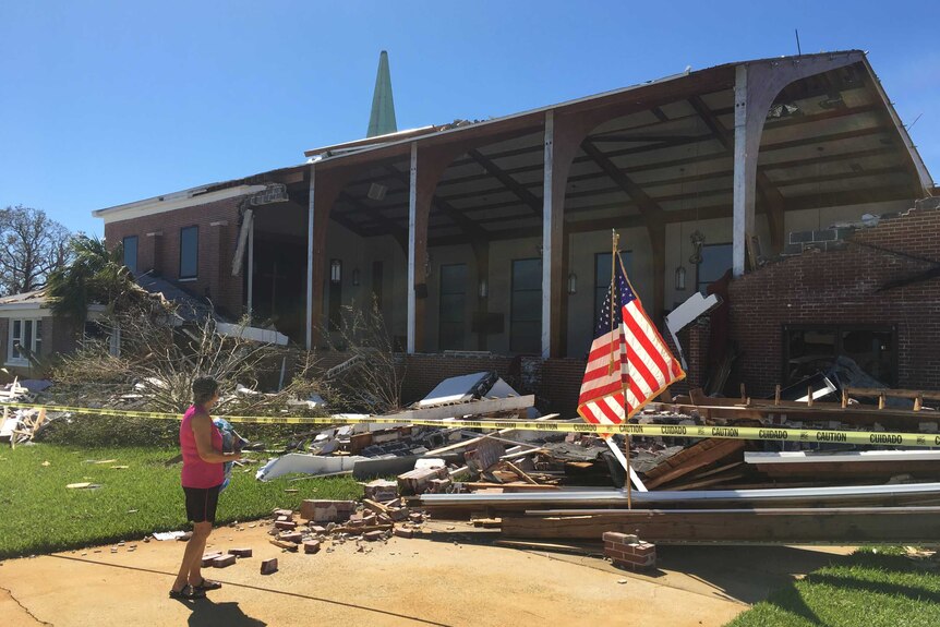 A woman stands outside a destroyed church
