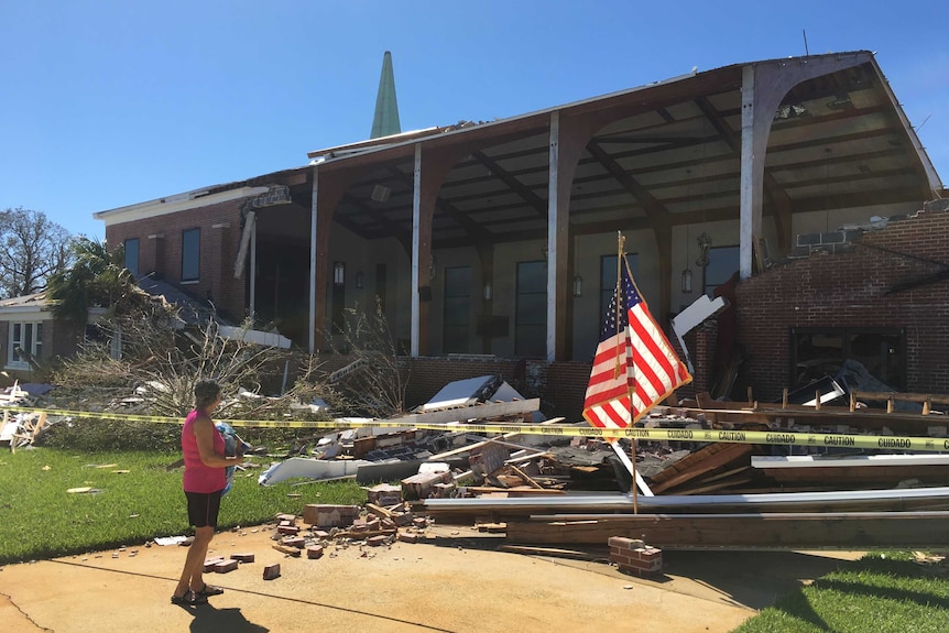 A woman stands outside a destroyed church