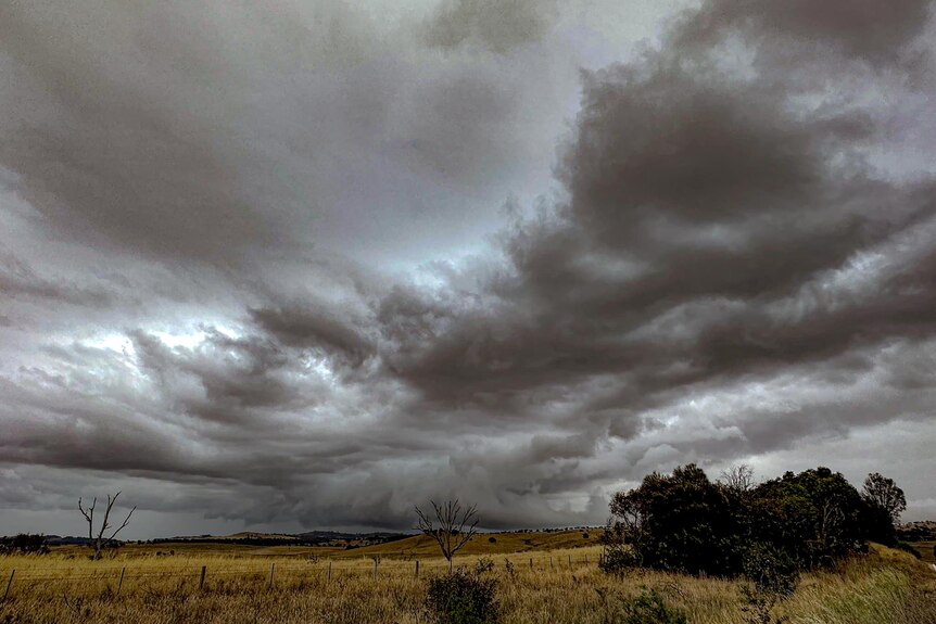 Dark grey clouds loom in the sky above farmland at Gunning in New South Wales
