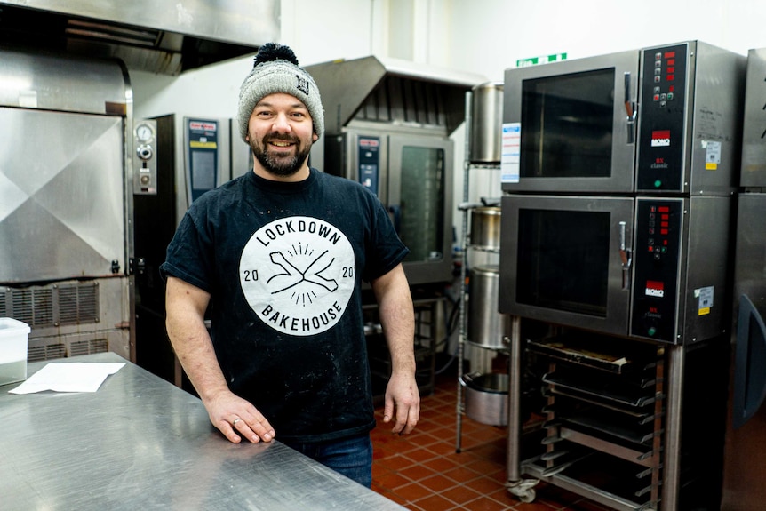 Australian baker Chris Brumby smiles and poses for a photo in a bakery.