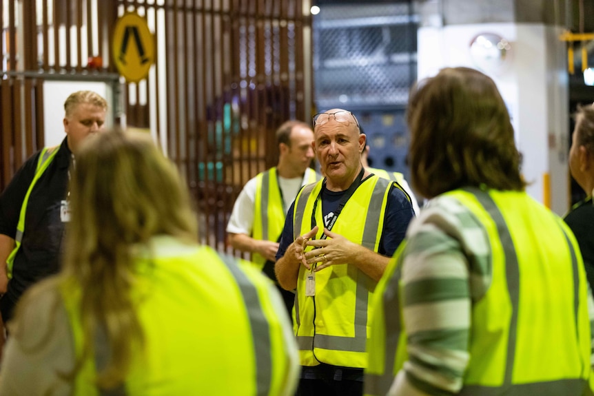 A man in high visibility addresses the volunteers