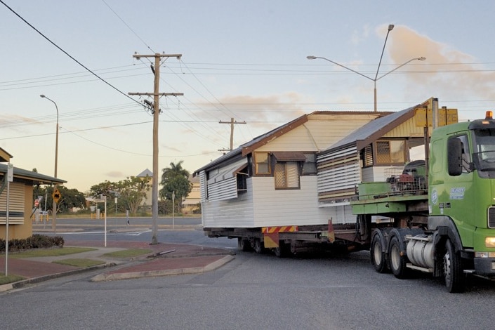 Truck tows a trailer with a house on it.