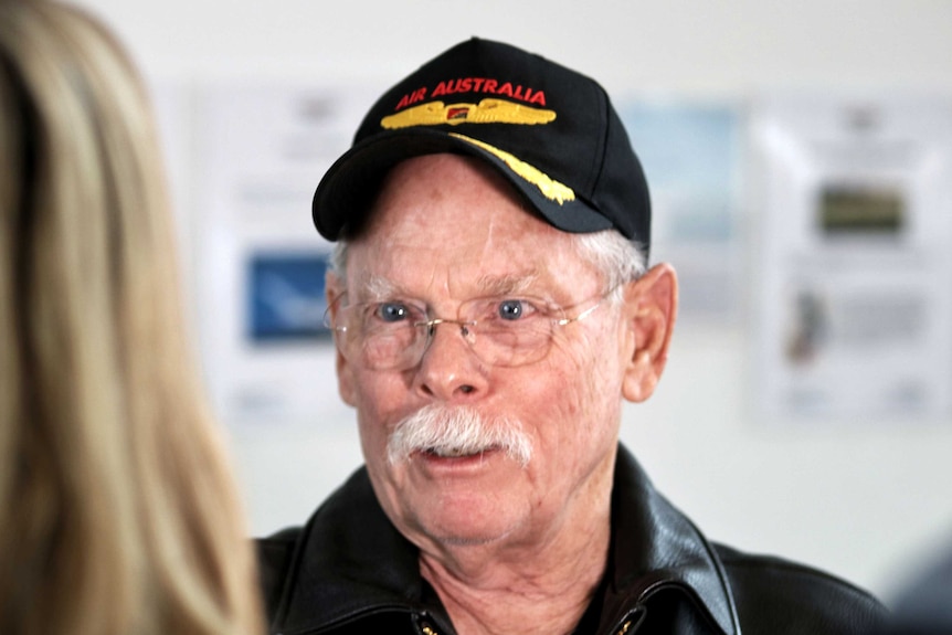 Headshot of a man in glasses and wearing a cap.