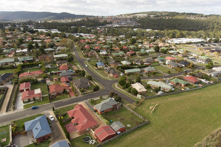 A bird's-eye view of houses and schools next door to a paddock.
