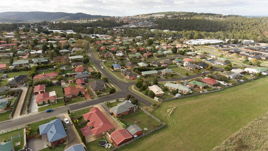 A birds eye view of houses and schools next door to a paddock.