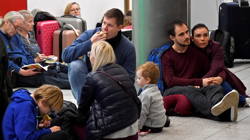 Passengers sit on the floor of Gatwick Airport