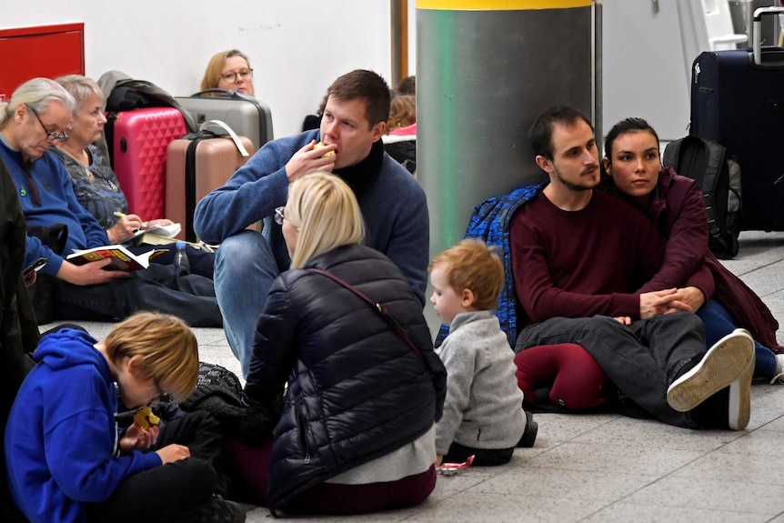 Passengers sit on the floor of Gatwick Airport