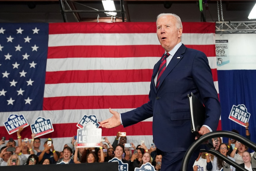 Joe Biden stands in front of a US flag