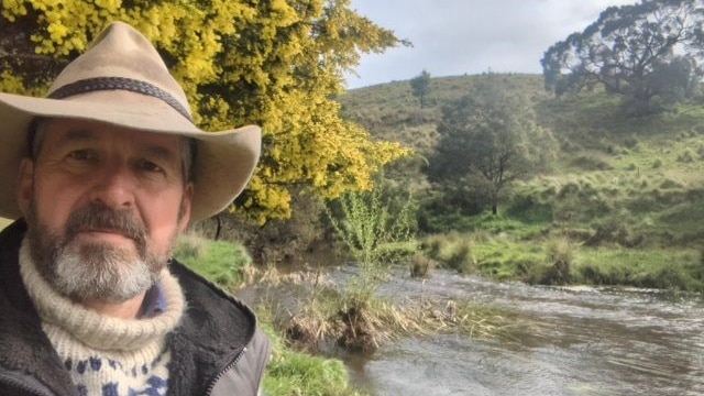 A picture of a farmer, selfie, with creek and bush in the background 