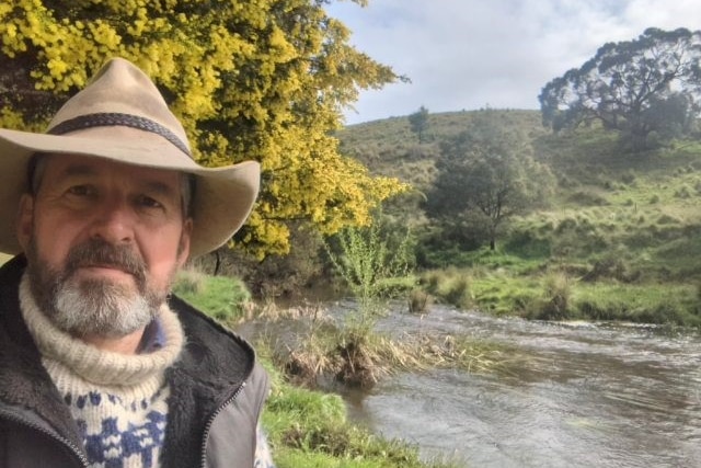 A picture of a farmer, selfie, with creek and bush in the background 
