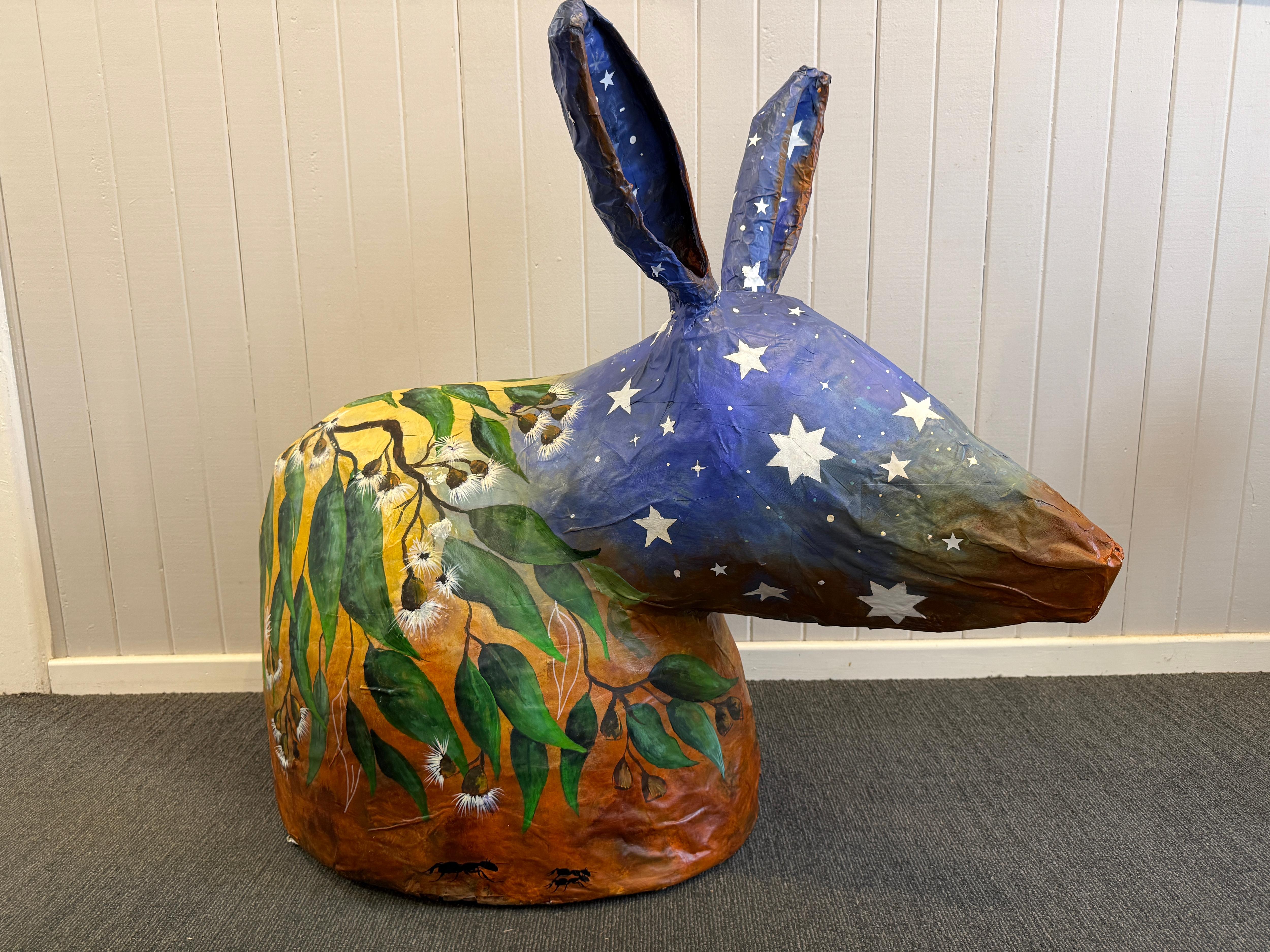 a large paper mache bilby with a star, gum leaf and red dirt design