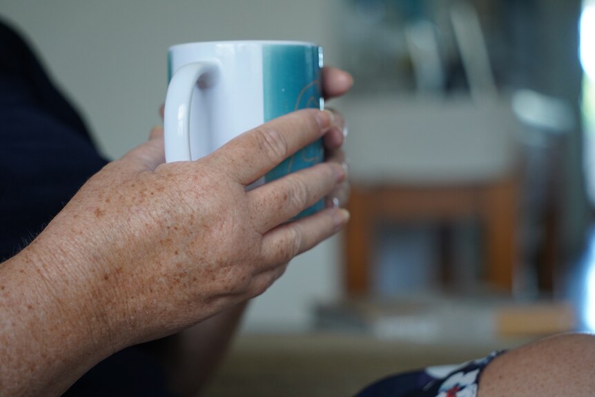 A close up of a woman's hands holding a mug.