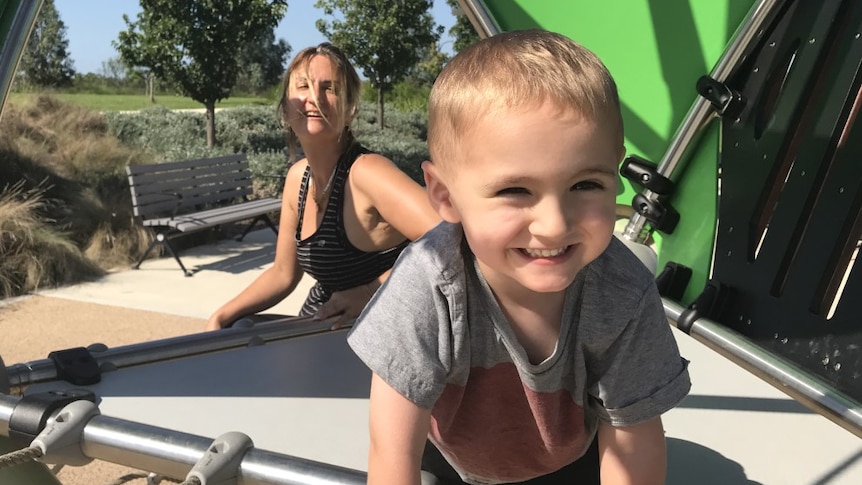 A woman and a young boy on playground equipment.