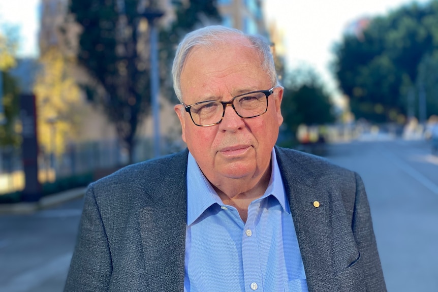 NSW Building Commissioner David Chandler stands outside with trees in the background.