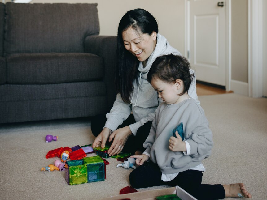 Woman and child sitting next to each other surrounded by toys