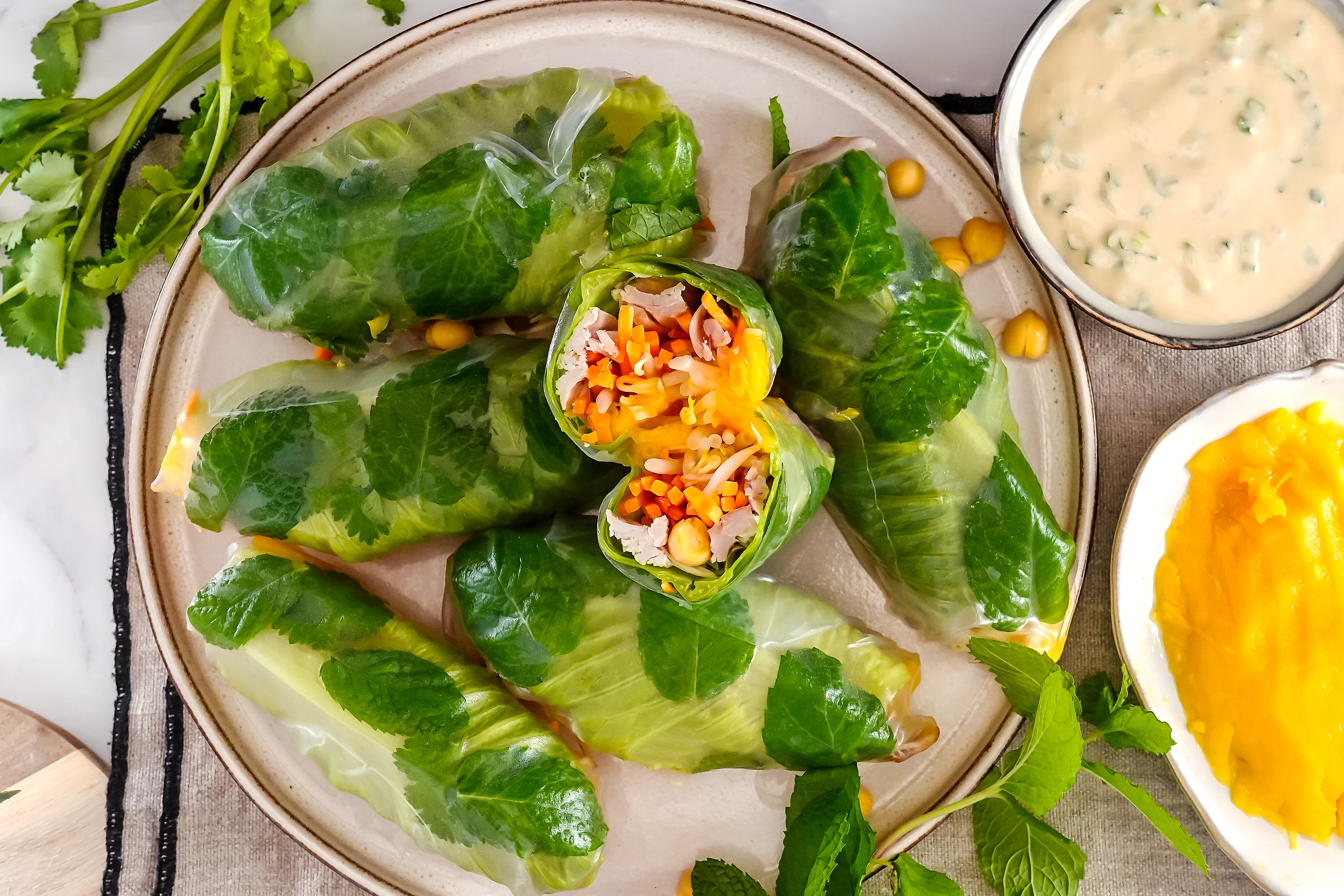 A plate of chicken and mango rice paper rolls, with one sliced open to display the salad and meat filling.