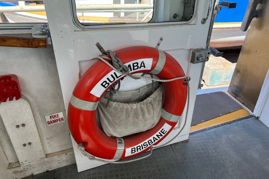 Lifebuoy with Bulimba, Brisbane written on it hangs on a will in a ferry.