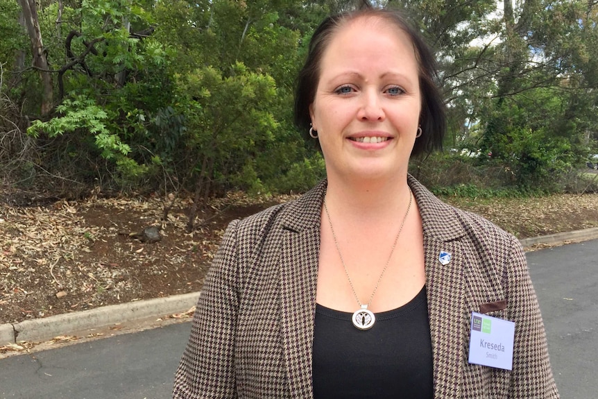 Dr Kreseda Smith stands facing the camera with green shrubbery behind her.