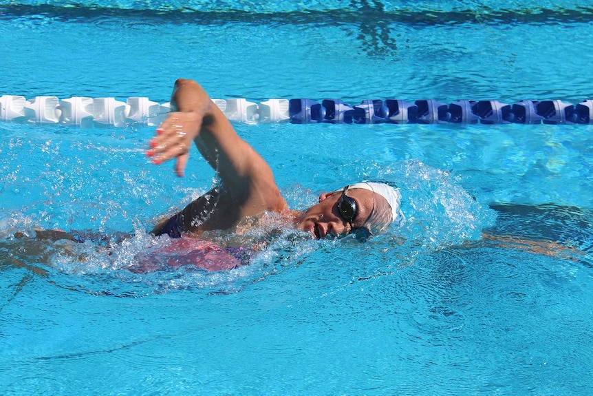 A woman swimming a lap in the lane of an Olympic pool