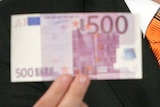 A hand holds a 500 Euro note