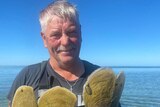 James Boylan standing in the ocean holding razorfish. 