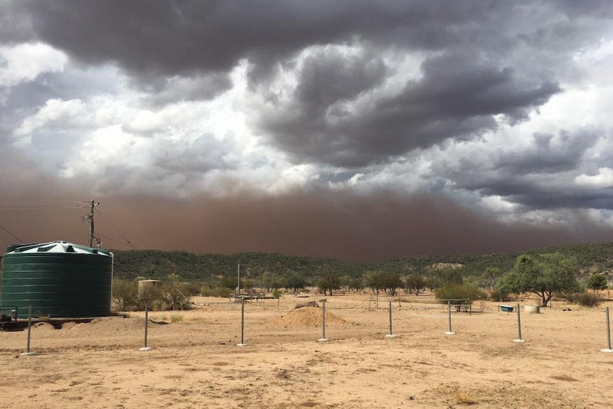 Dark ominous clouds above a dusty property with a water tank in Hughenden.